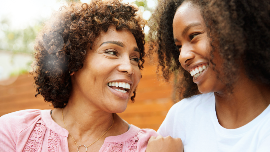 African American Mom and teen daughter laughing.