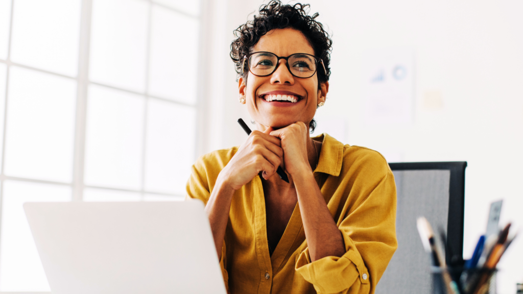 Black lady with a gorgeous smile sitting at her desk.